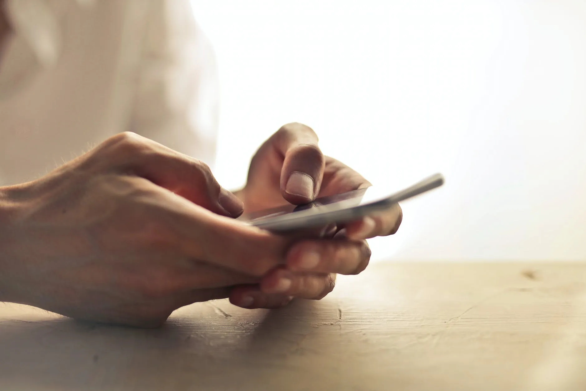 Hands using a smartphone beside a window